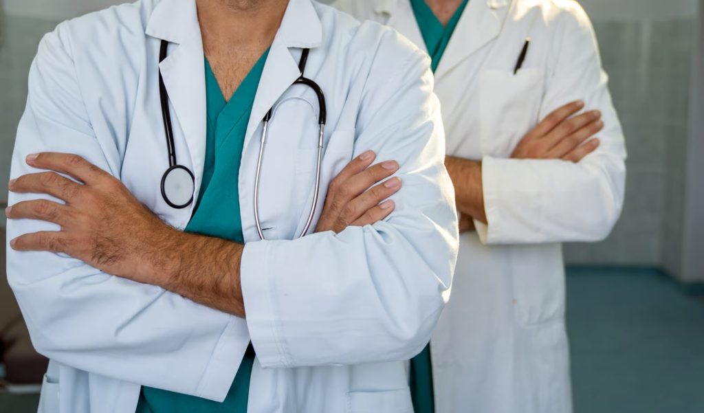 Dois médicos de bata branca, de braços cruzados